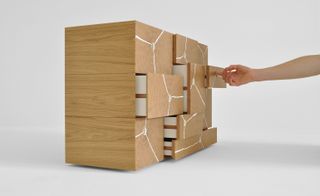 ’Log Stack Cabinet’, white room, pale colour wood drawer unit with some pulled open, hand reaching out opening a drawer, white crackle effect to the front of the drawers