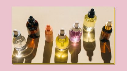 Glass bottles for cosmetic products with pipette, on beige and pink background. 