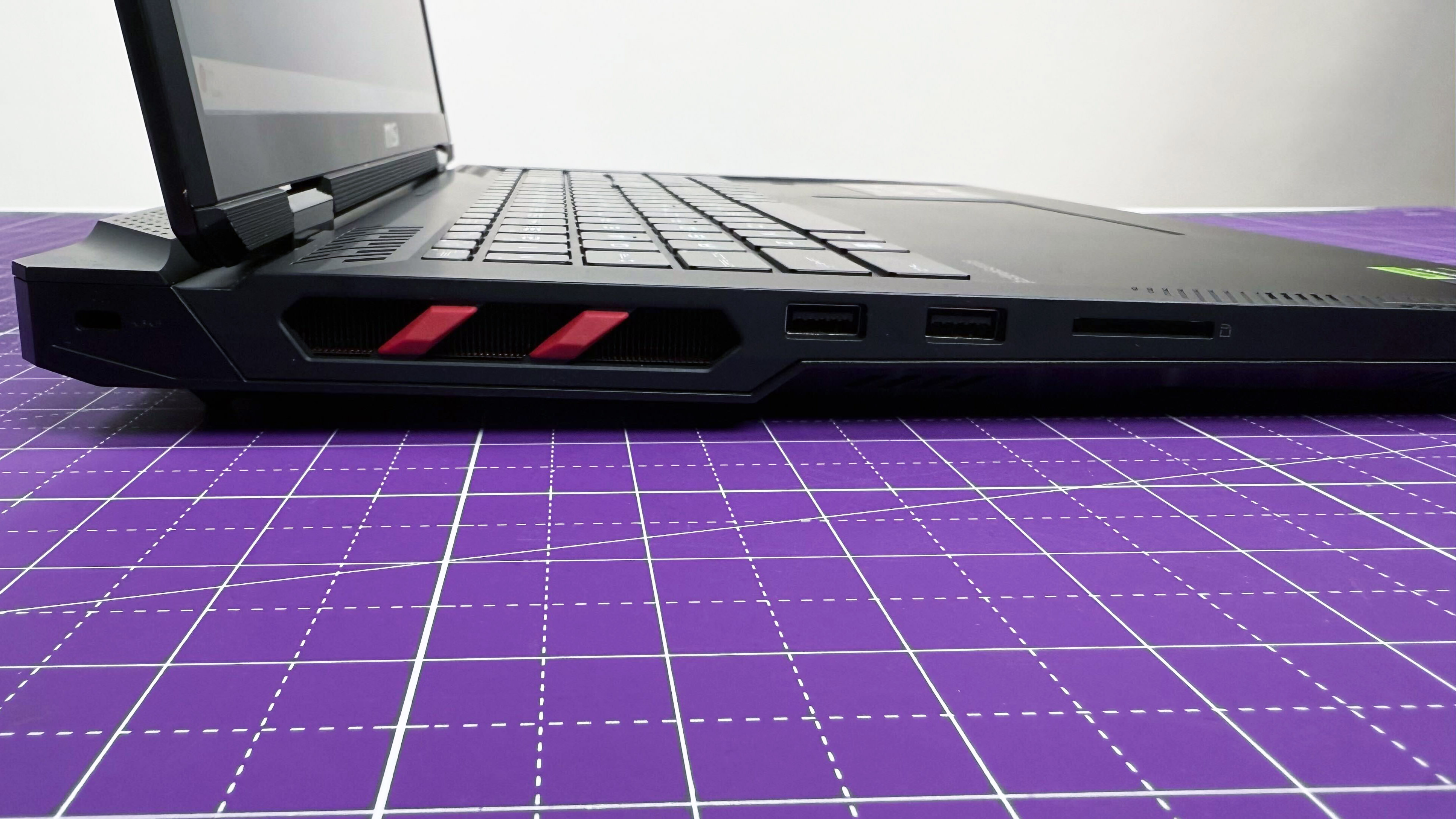 Close up of the left-side ports on the MSI Raider 18 HX AI gaming laptop on a purple mat against a gray background.