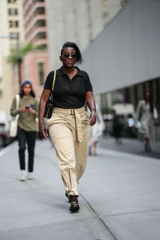 nikki ogunnaike in a black polo shirt and tan cargo pants