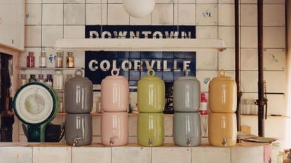 A vintage backdrop with five glazed ceramic water filter dispensers in gray, pink, green, blue and yellow