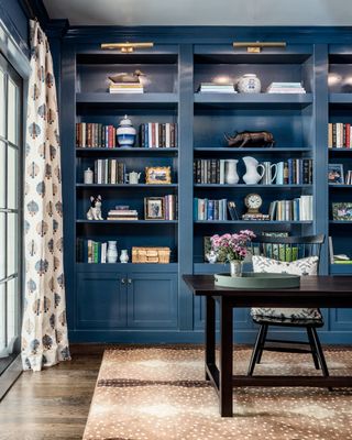 A living room with built-in shelving painted a mid blue and displaying books and decor items