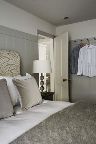 Bedroom with wood panelled walls in grey and grey ceiling and peg rail for clothing