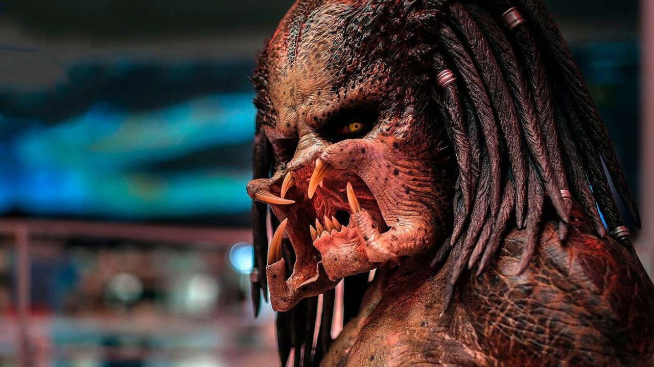 Close up image of the alien Predator's face. It has shoulder-length dreadlocks and sharp mandibles.