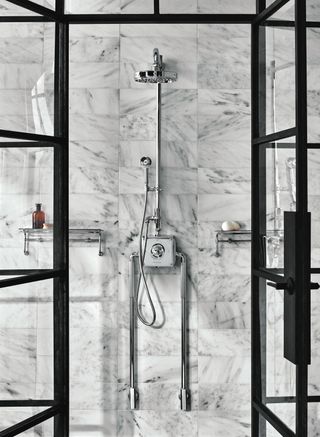 marble tiled shower wall with chrome shower and black framed glass shower doors