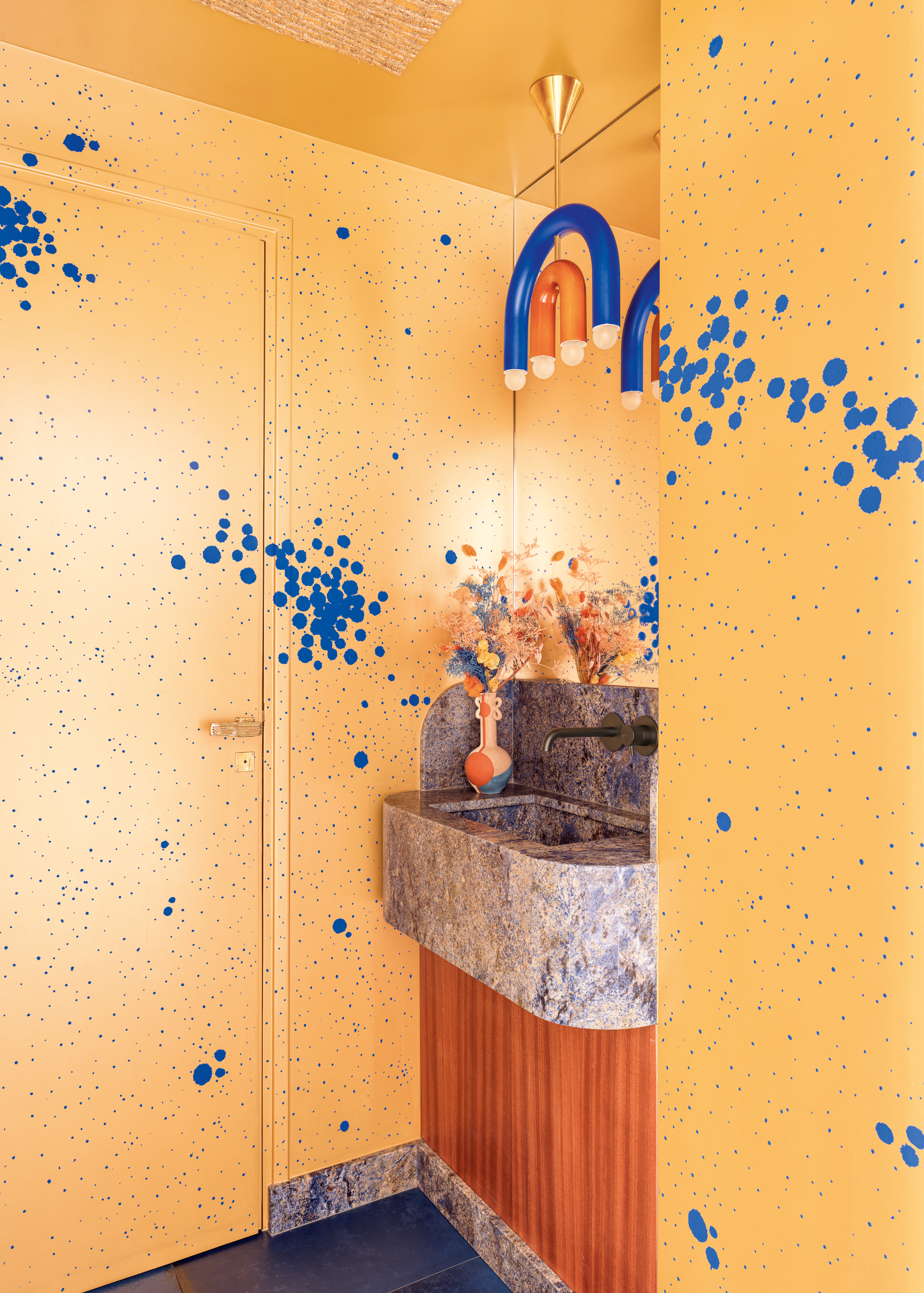 Powder room with yellow and blue-splattered walls and wood and blue marble sink