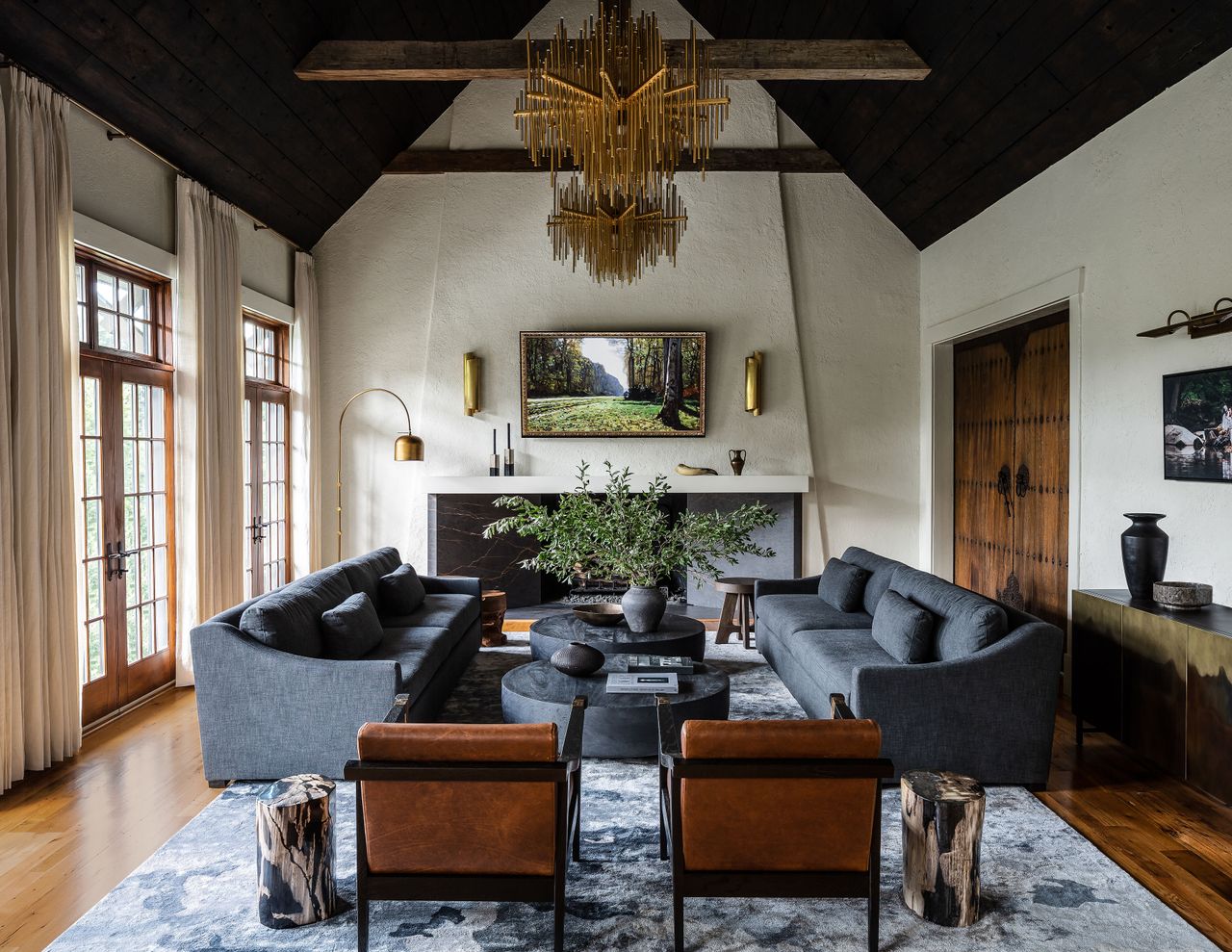 A large living room with a dark vaulted ceiling, two blue sofas facing one another, and a large fireplace