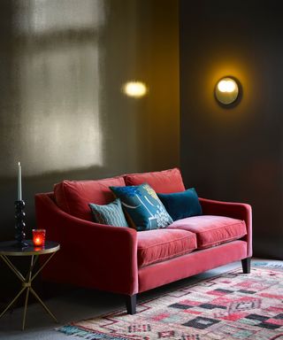 colors that go with dark green, green living room with scarlet couch, vintage rug, wall lights, metal side table, blue cushions