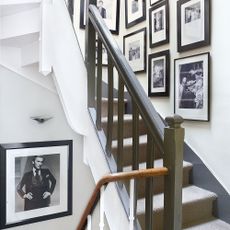 White and black staircase with black framed photographs arranged on a white wall