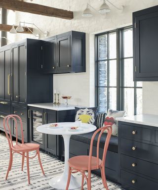 An indigo kitchen with gold hardware, white walls, and white countertops