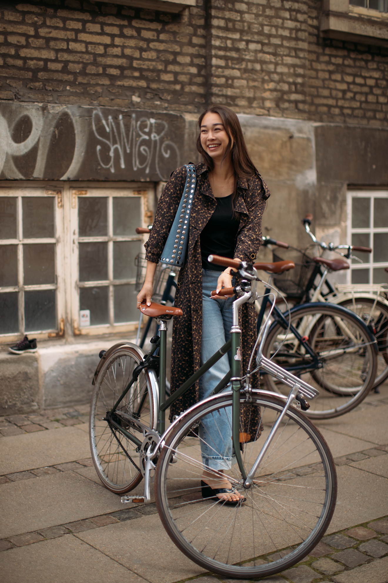 a guest at Copenhagen Fashion Week wearing flip flops with jeans and a long jacket