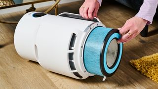 A white Shark NeverChange air purifier showing the HEPA filter being removed through the base.