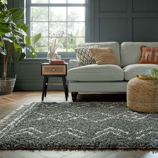 Dunelm Carina Berber Rug in dark living room with grey sofa and rattan side table