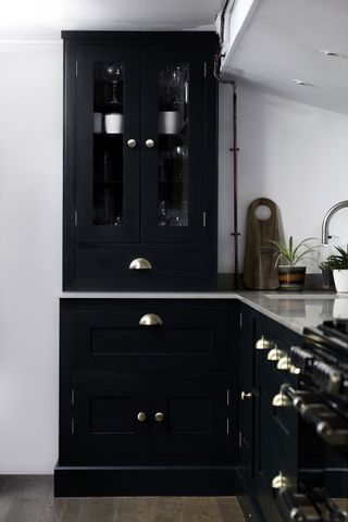 Kitchen with dark cabinetry, pale worksurface and white walls