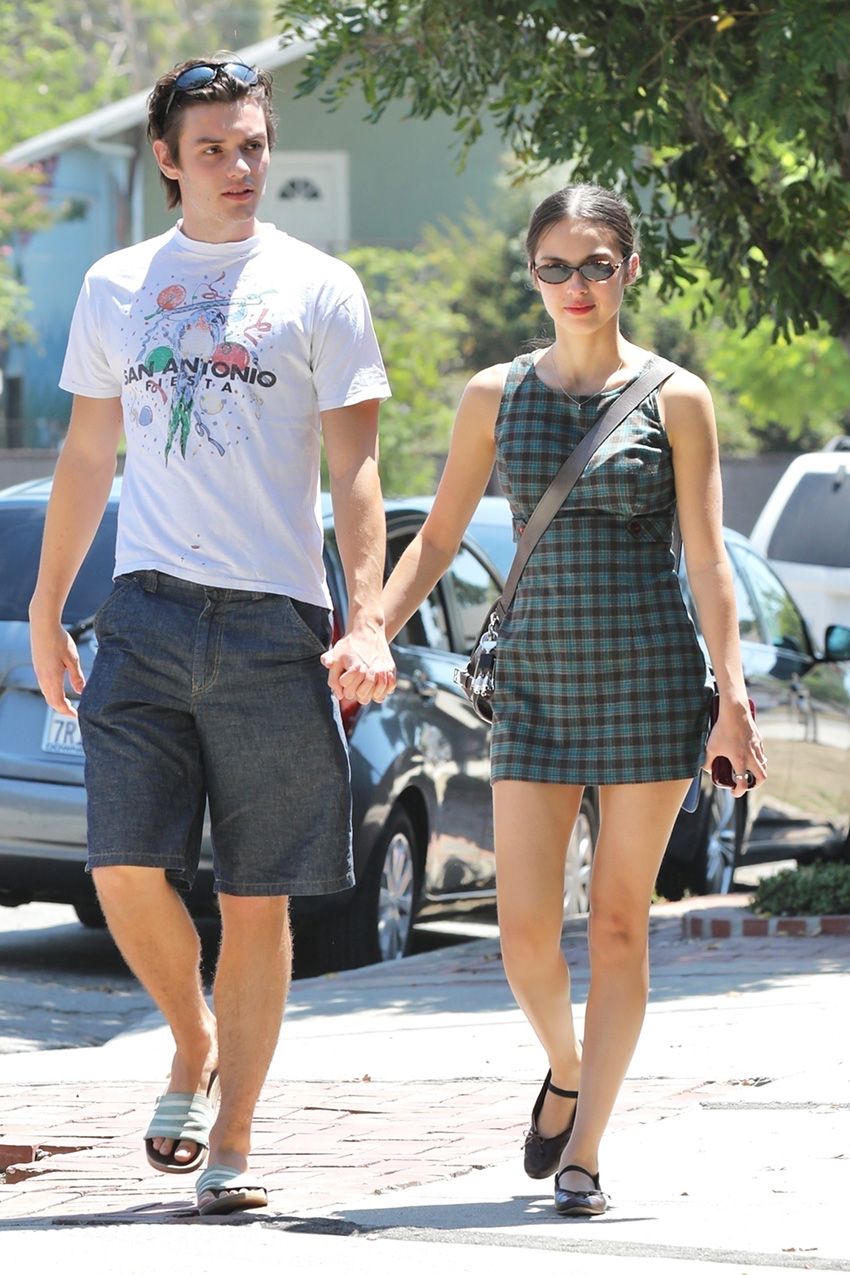 Olivia Rodrigo wearing a plaid dress walking with boyfriend Louis Partridge