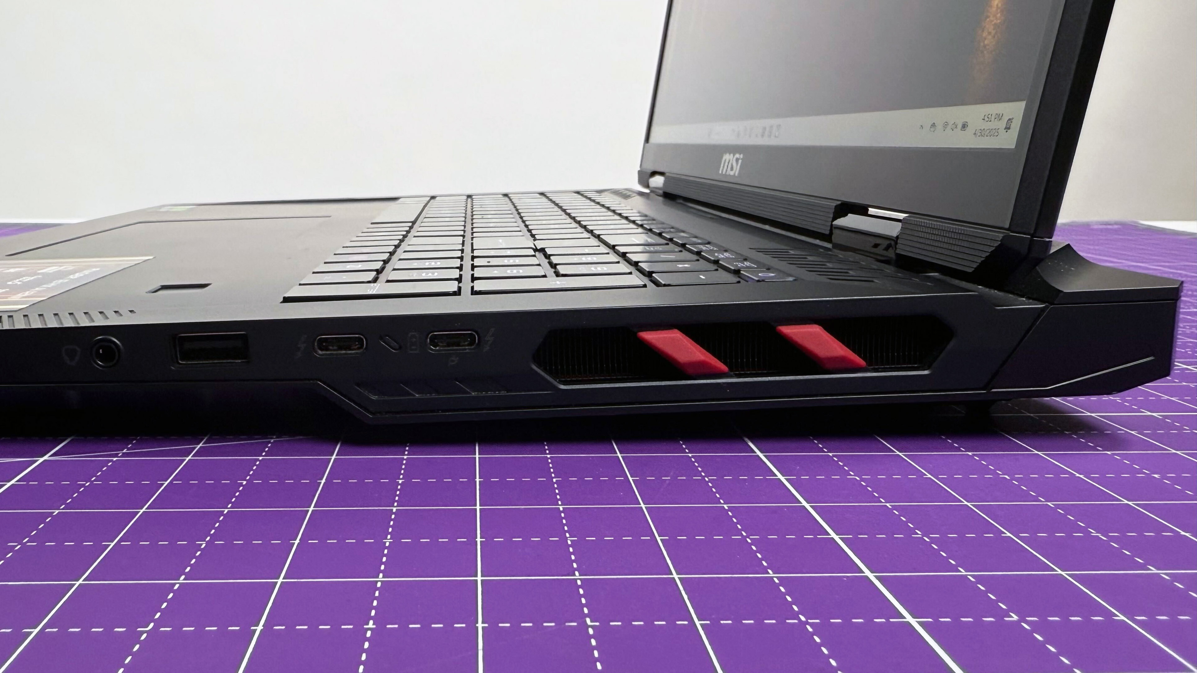 Close up of the right-side ports on the MSI Raider 18 HX AI gaming laptop on a purple mat against a gray background.