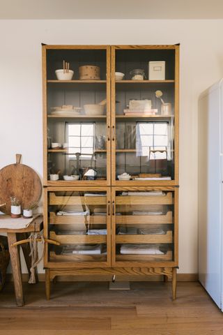 a wood and glass organized kitchen cabinet sat on a matching wooden floor