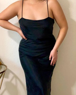 Fashion influencer Marina Torres poses with her hand on her hip wearing a black spaghetti strap slip dress.