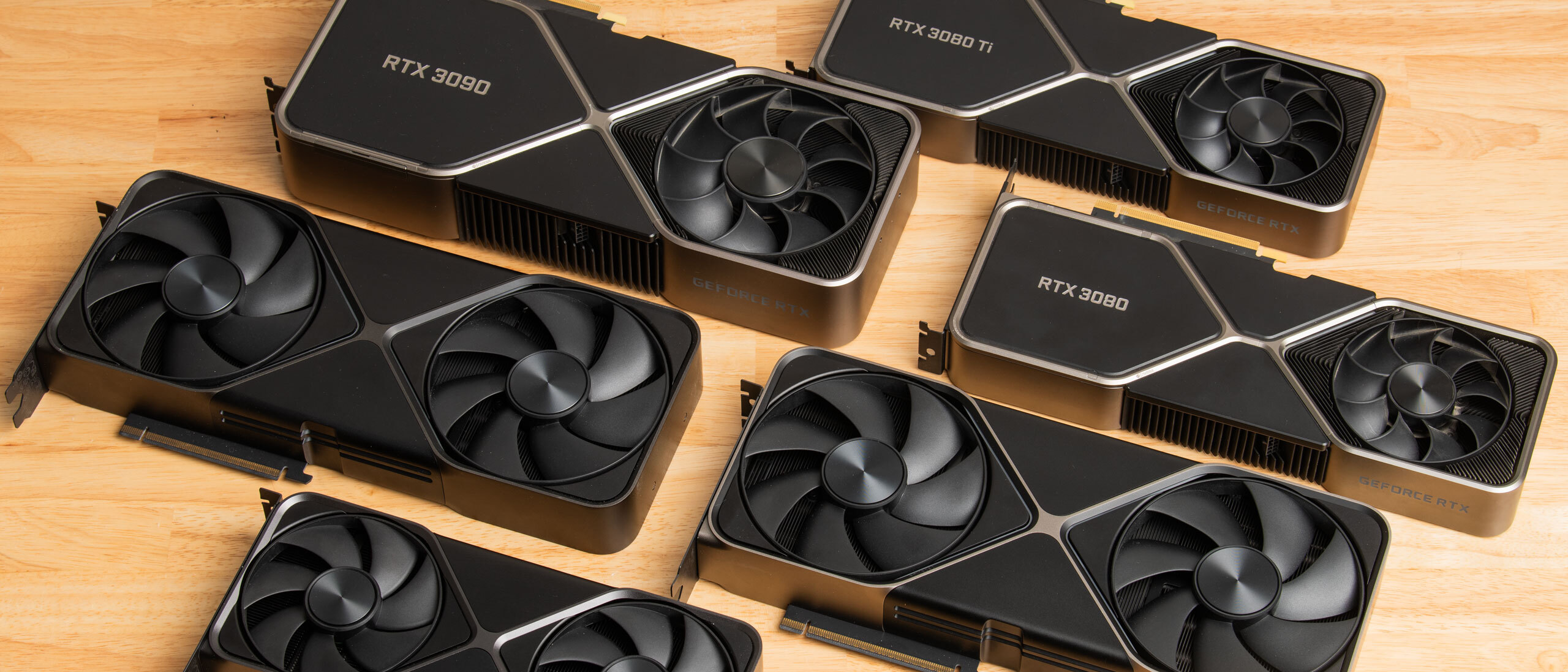 An array of RTX 30-series GPUs on a wooden desk.