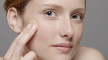 woman&#039;s face, applying concealer