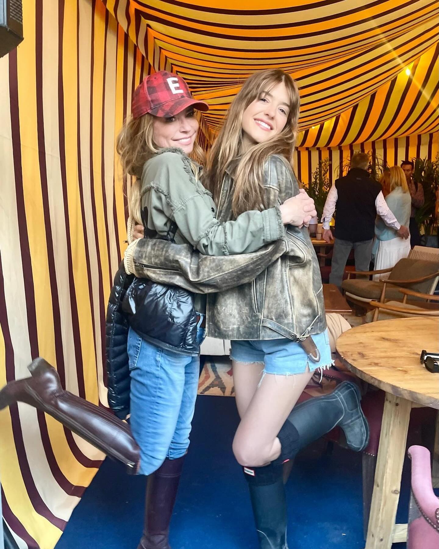 Daisy Edgar Jones hugs a friend in a Glasto tent, she's is wearing a leather jacket hunter boots and blue denim shorts in an image taken from her instagram last year.