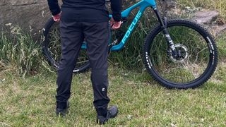 Rear view of man wearing Mons Royale Virage Pants with bike and grass backdrop