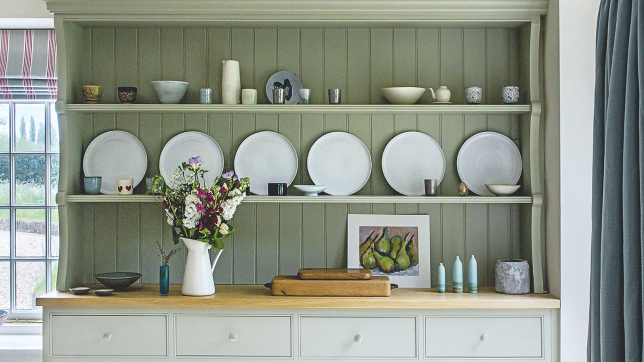 Large pale green dresser on a tiled floor. Historic family home in the Cotswolds, a five bedroom converted 17th century mill house, home of Cat And Sim Preston and their family