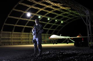 U.S. Air Force Airman 1st Class Damian Guardiola, a 407th Expeditionary Security Forces Flight member, guards a Predator drone on the Ali Air Base in Iraq on Aug. 28, 2011.