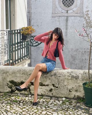 a woman wears a pink cardigan with denim shorts