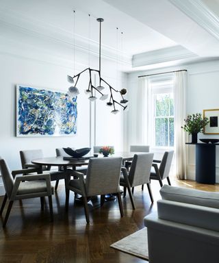 dining room with oval table and upholstered chairs and blue artwork and glass contemporary chandelier