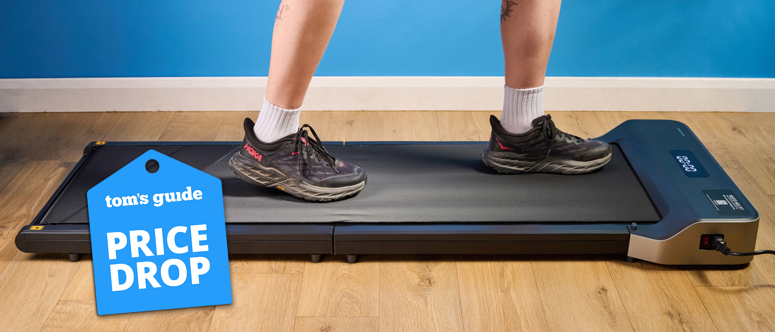 The WalkingPad Z1 foldable treadmill with a woman walking on it in Hoka running shoes and a price drop tag.