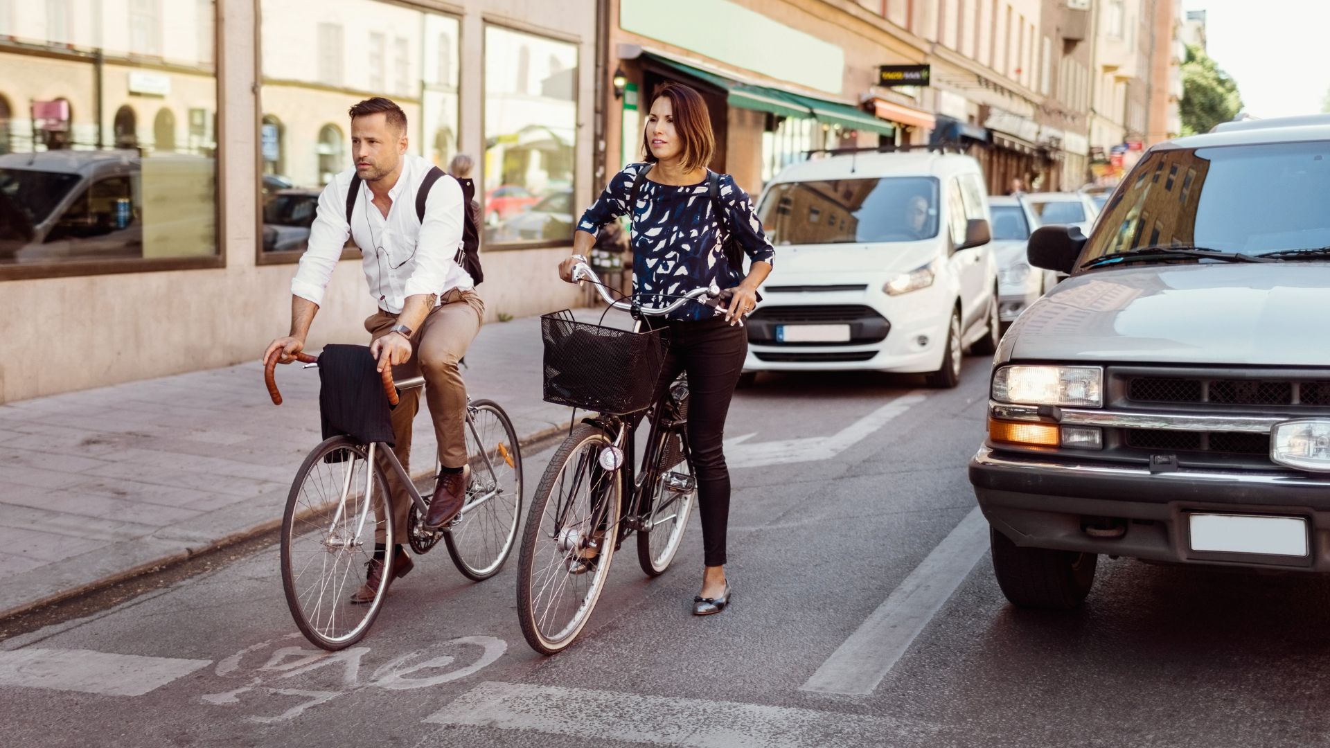 Woman cycling next to car