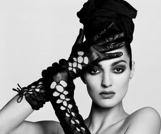 a model wearing black leather gloves posing agains a white backdrop