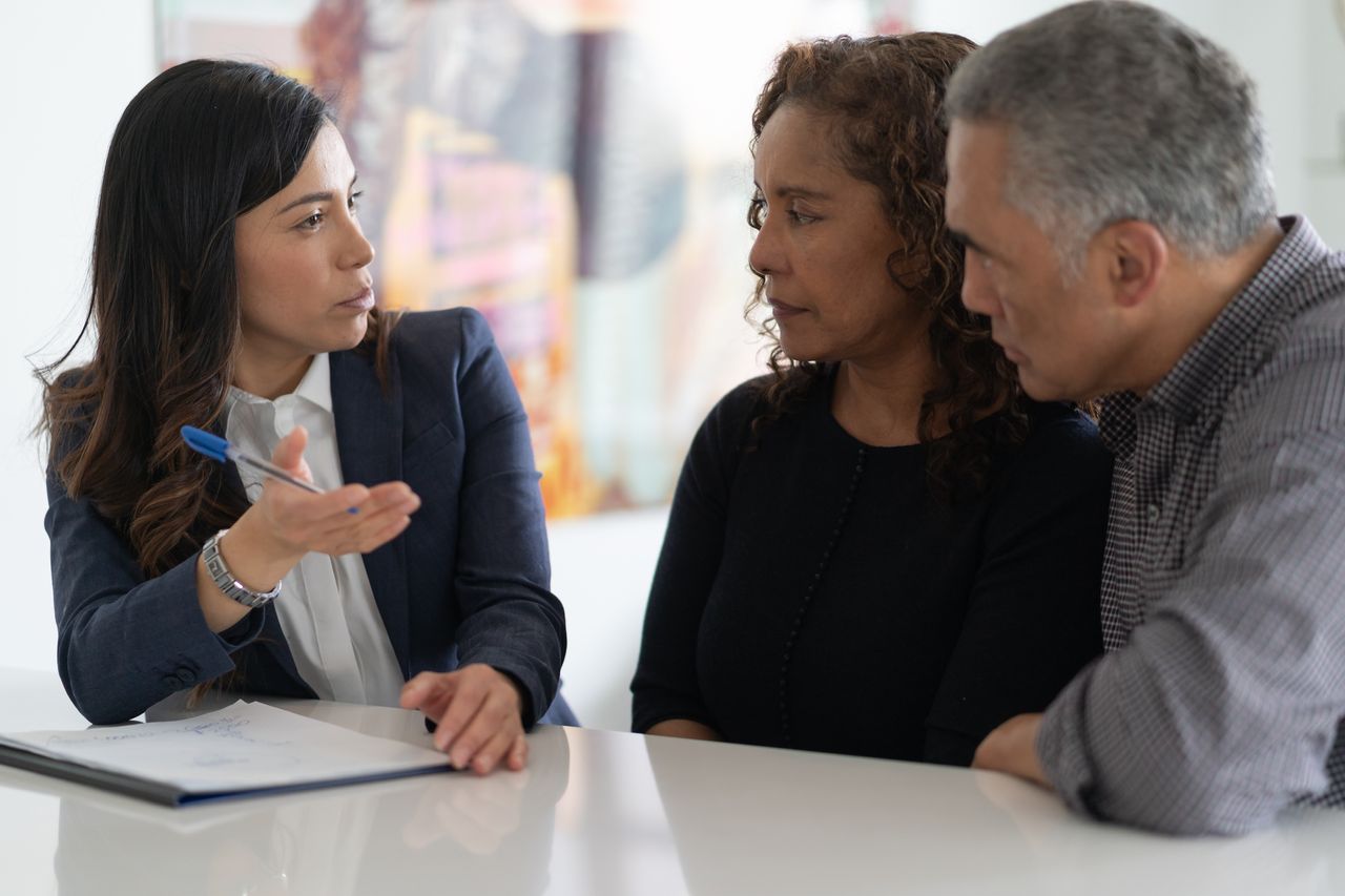 A couple is in a meeting with their financial advisor. They are devising a financial plan at their kitchen table.