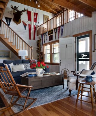 A lake house-style living room, with wooden raftered ceilings, a red, white and blue color scheme and bright red flowers