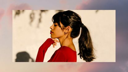 Young woman with a ponytail standing with hand on chin by tree shadow during sunset - stock photo