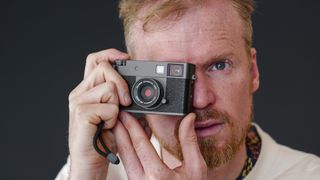 Fujifilm X half compact camera being held up to person's eye