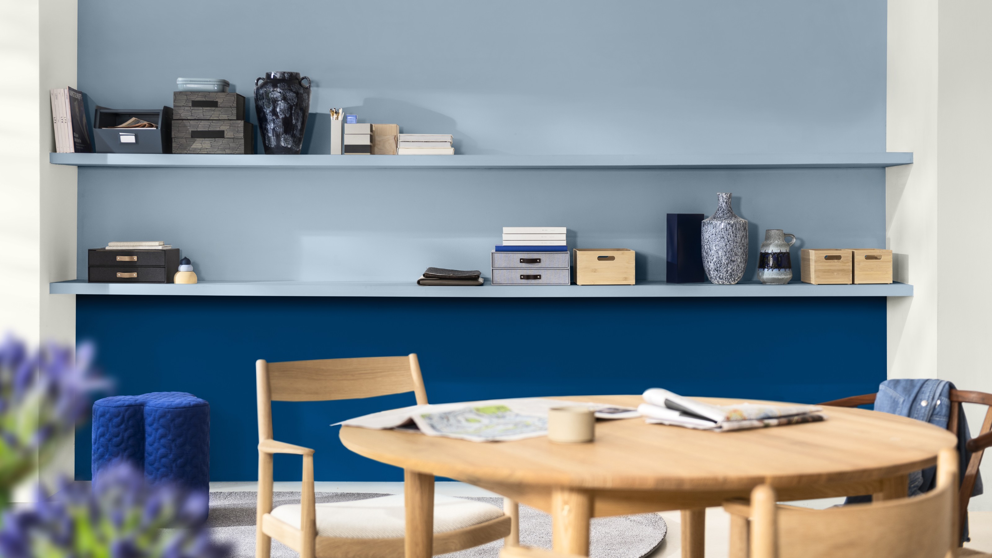 A dining area with a wall featuring floating shelves painted half in Dulux's Free Groove shade and half in Mellow Flow