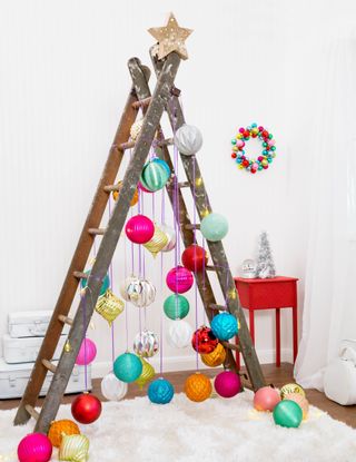 A large ladder with colorful Christmas bauble decor, faux fur rug and red wooden side table