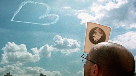 A man shields his eyes from the sun using the programme from a memorial service for Diana in New York