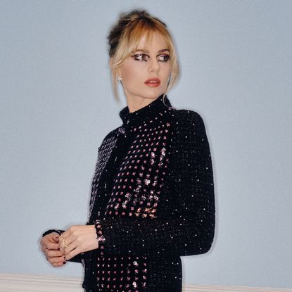 Lucy Boynton in front of a blank wall wearing Chanel