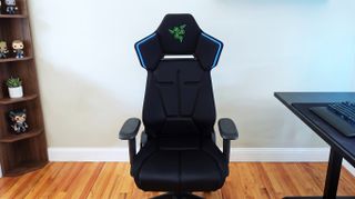 A full front shot of the black Razer Soma Chroma gaming chair on a wooden floor, showing its blue LED accents.