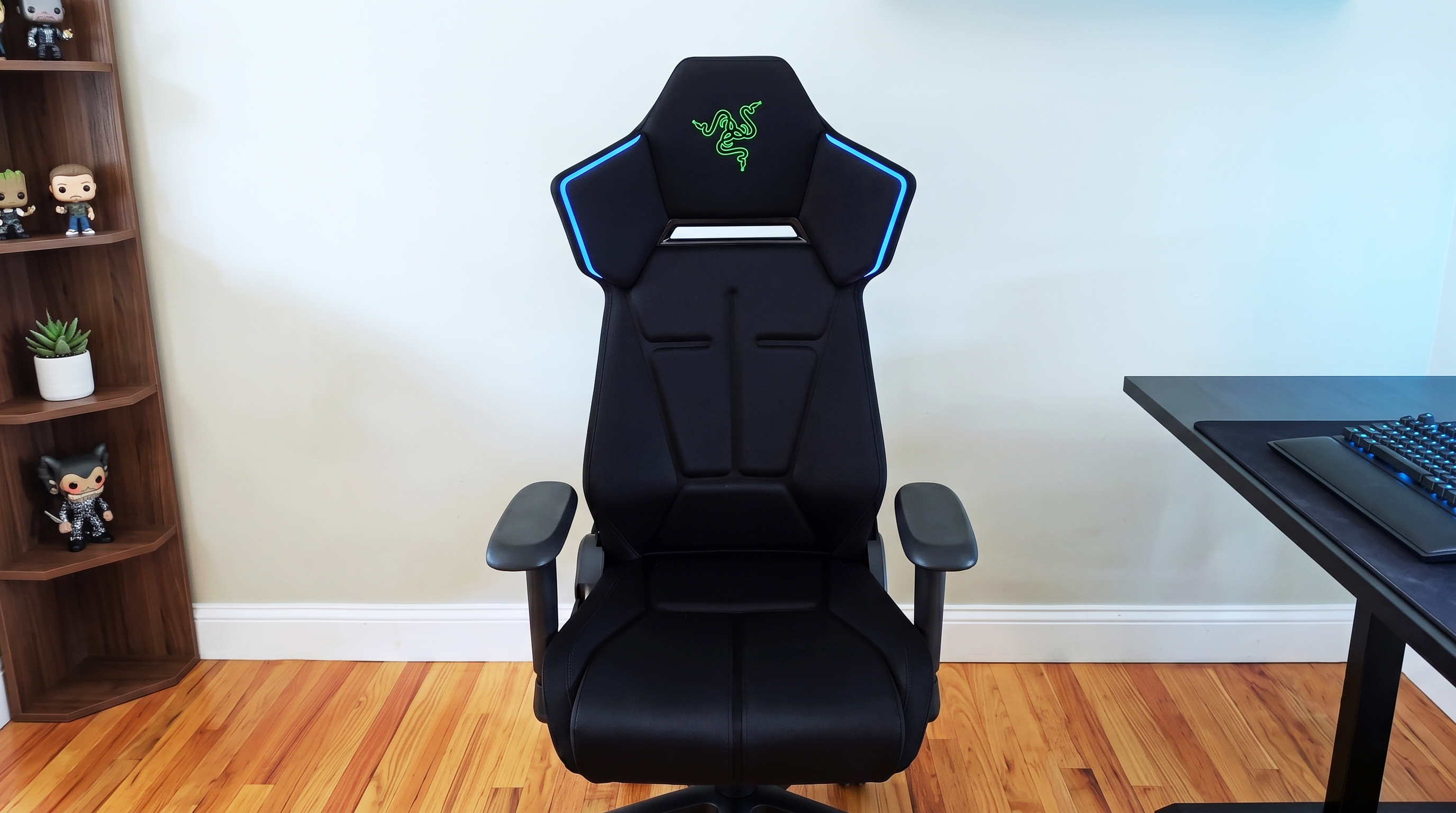 A full front shot of the black Razer Soma Chroma gaming chair on a wooden floor, showing its blue LED accents.