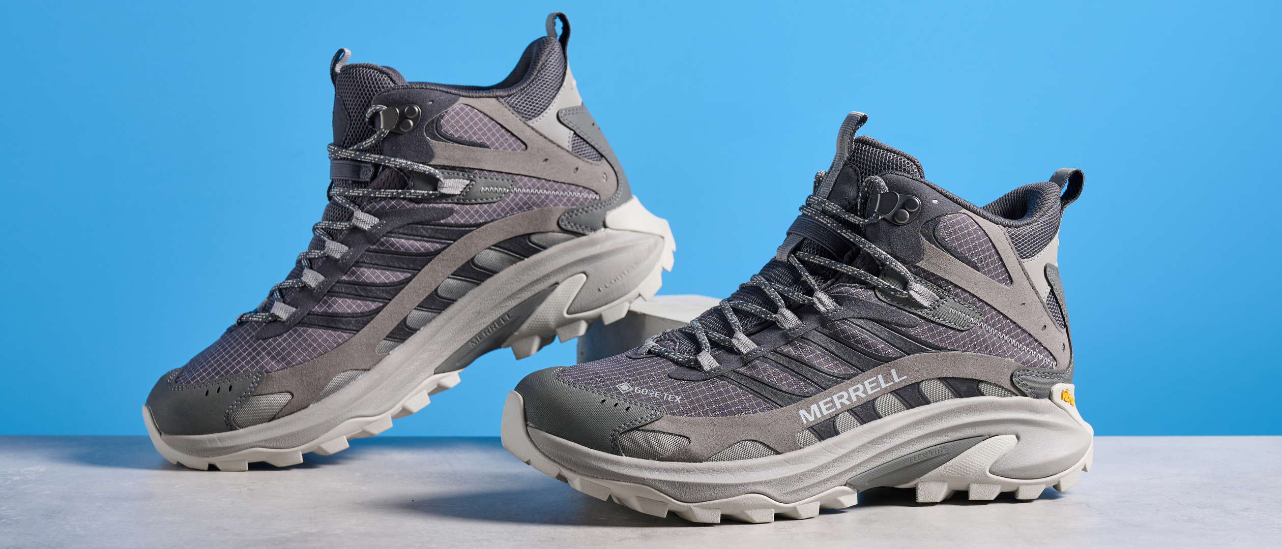 A photo of the Merrell Moab Speed 2 boots against a blue background