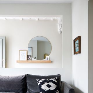 neutral hallway with cut out wall with mirror and sofa