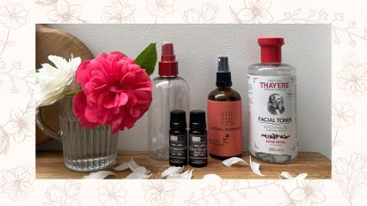 Bottles of ingredients needed to make a DIY face mist pictured next to flowers in a glass cup