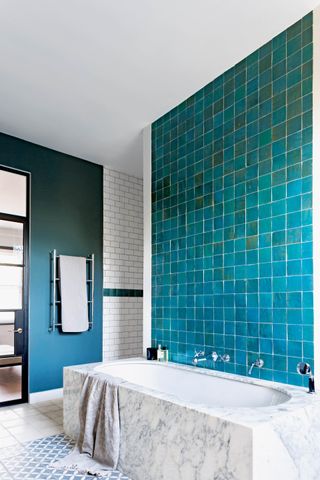 Blue tiled bathroom with square tiles and marble bath
