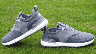The grey True Linkswear Lux Hybrid Golf Shoe resting on the golf course showing off its athletic profile and mesh design