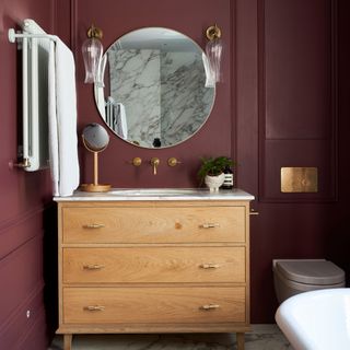 Bathroom with maroon wood panelled walls, grey and white marbled floor, handbasin in wooden chest of drawers vanity unit