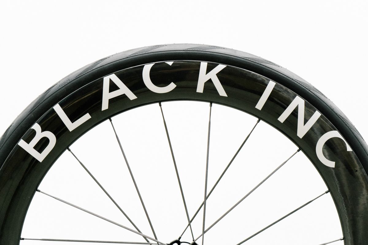 An aero road wheel stands against a white wall
